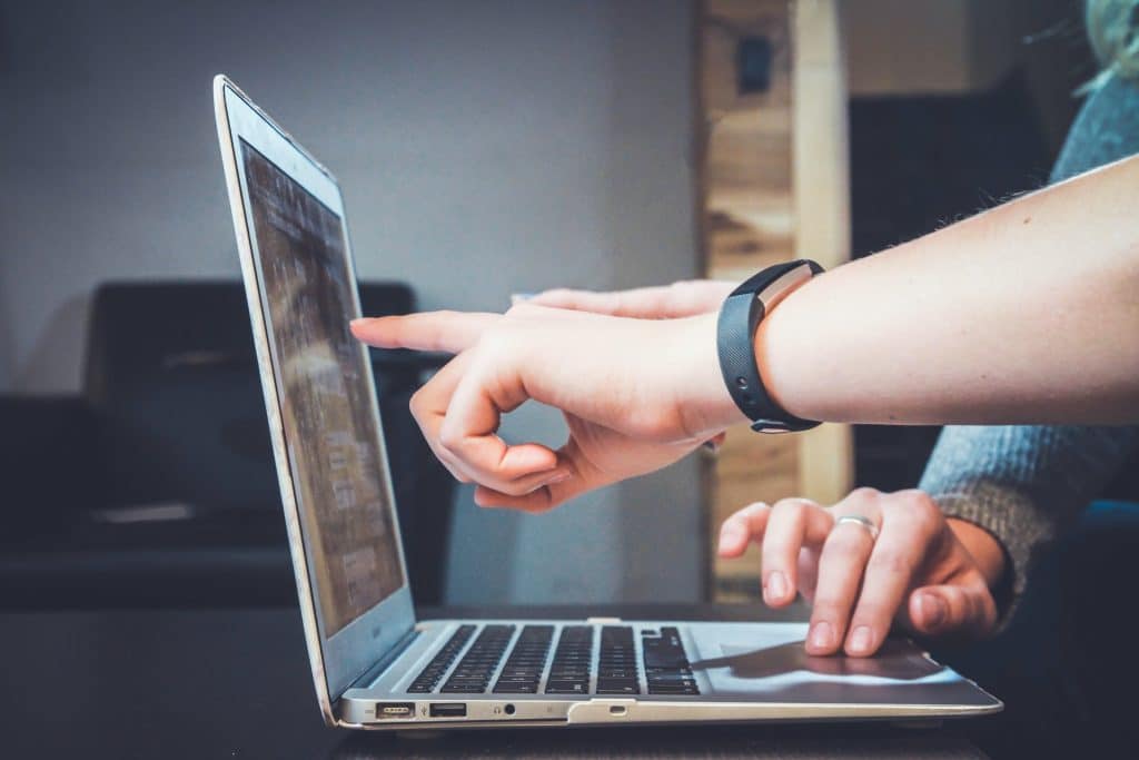 person pointing on the laptop