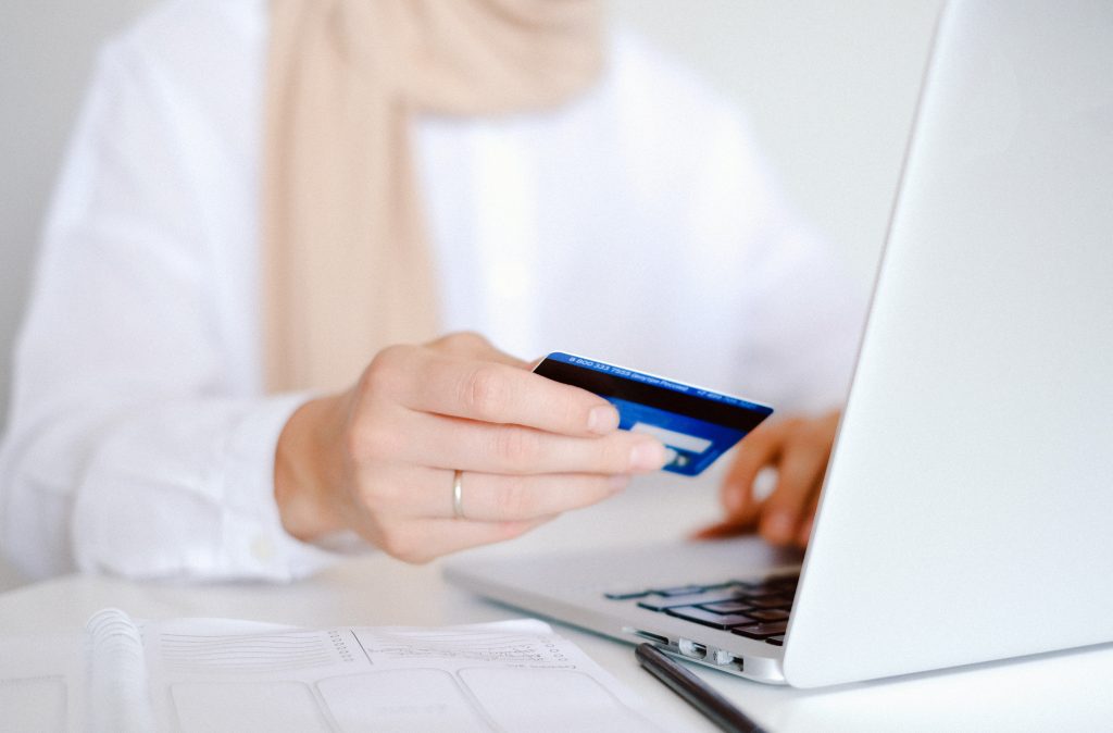 person in white long sleeve holding a credit card