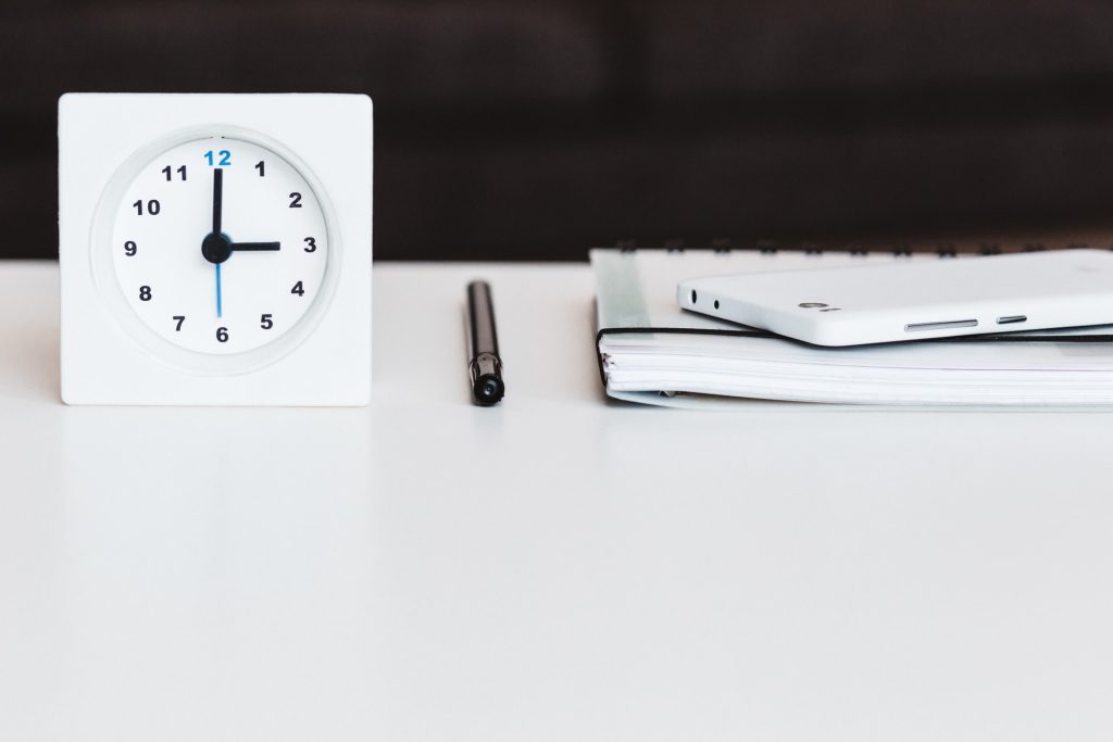 white smartphone near white clock